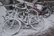 844961 Afbeelding van geparkeerde, besneeuwde fietsen, vermoedelijk op de Zandbrug te Utrecht.